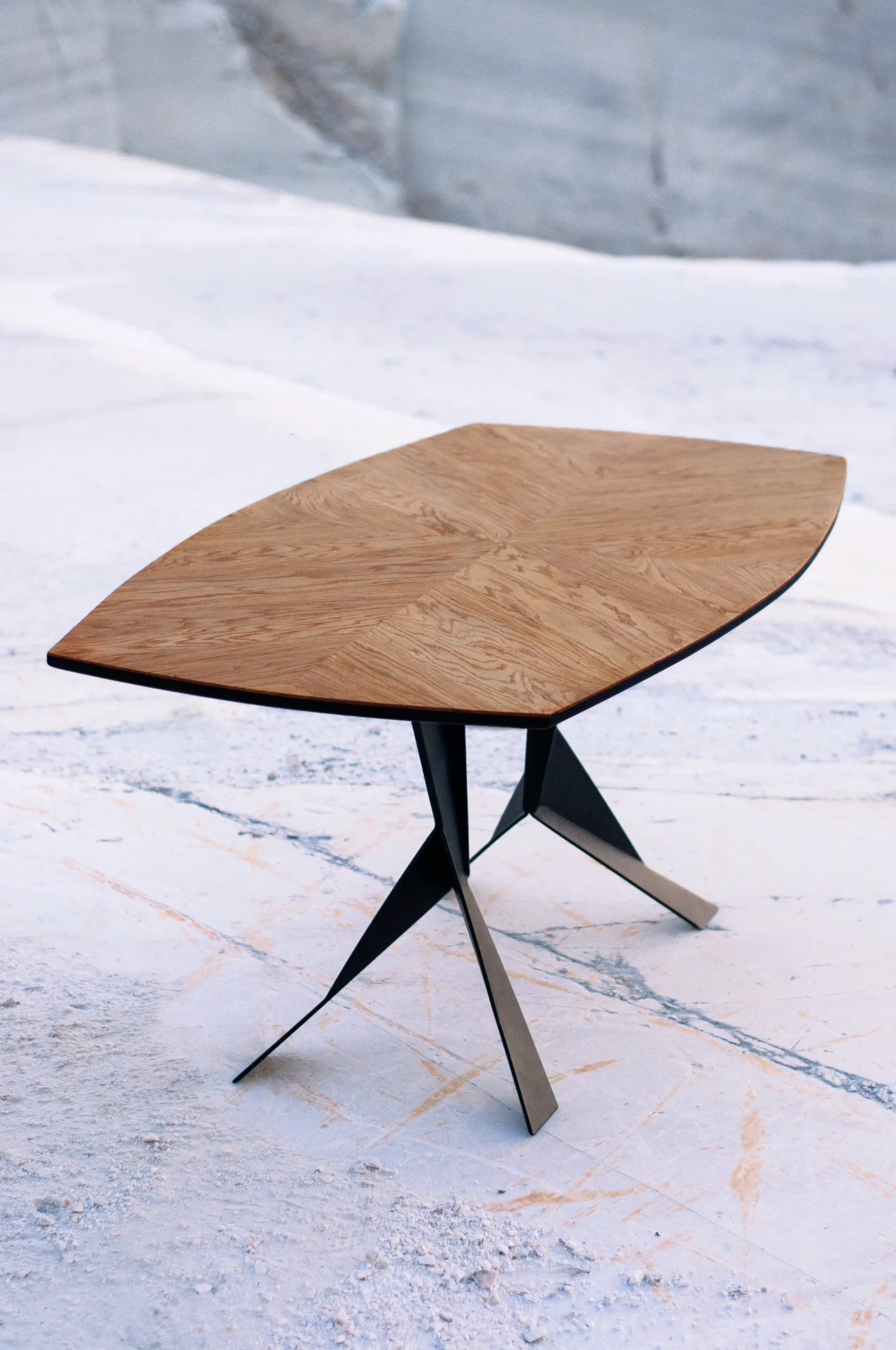 The Parabola dining table is a wooden table with handmade steel legs.